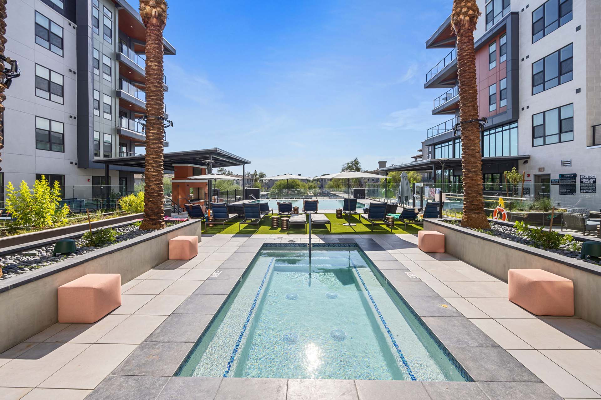 The pool area at Soltra Kierland apartments for rent in Scottsdale, AZ, featuring outdoor furniture and palm trees.