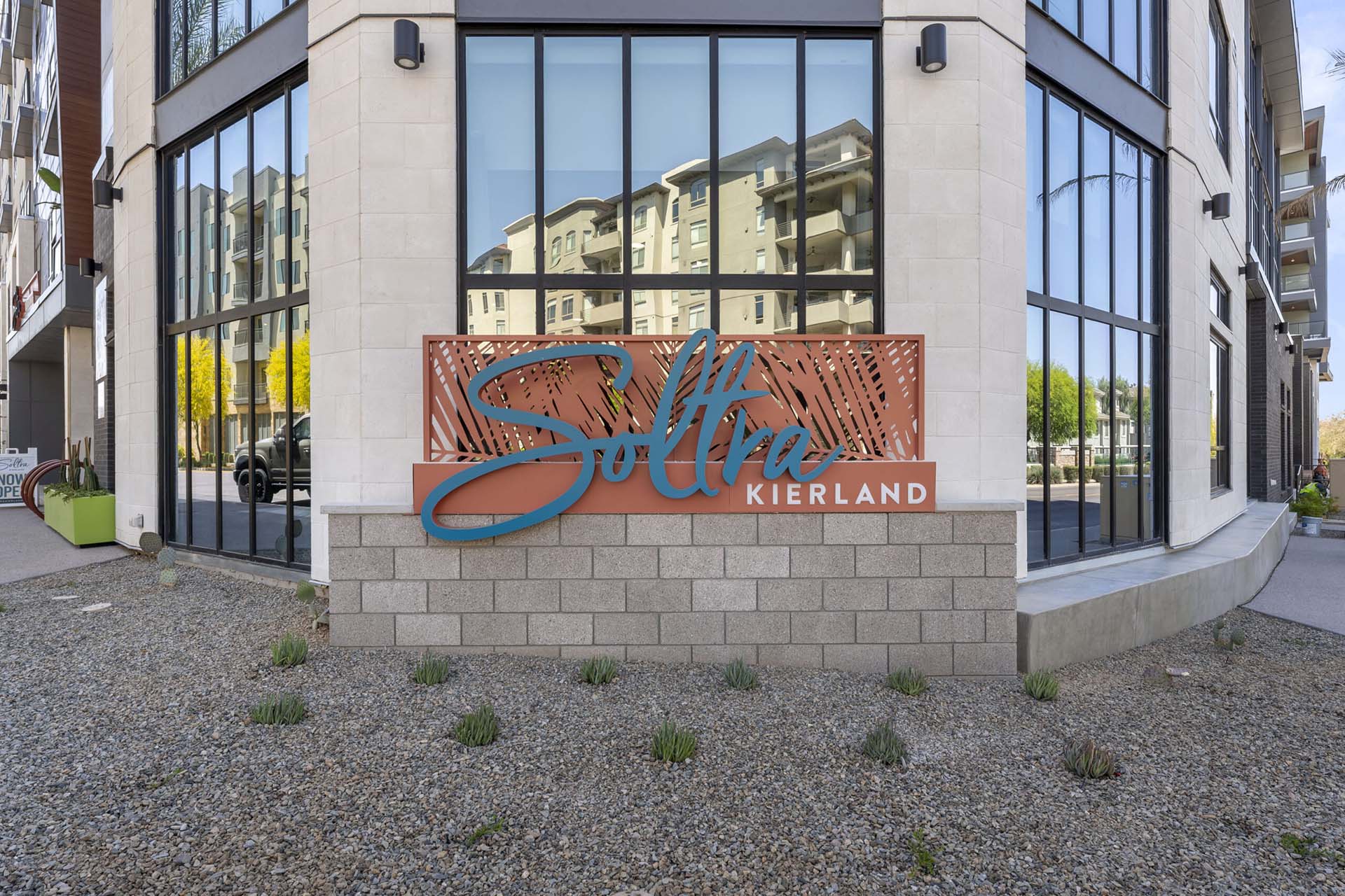 The entrance sign for Soltra Kierland apartments for rent in Scottsdale, AZ, featuring large glass windows.